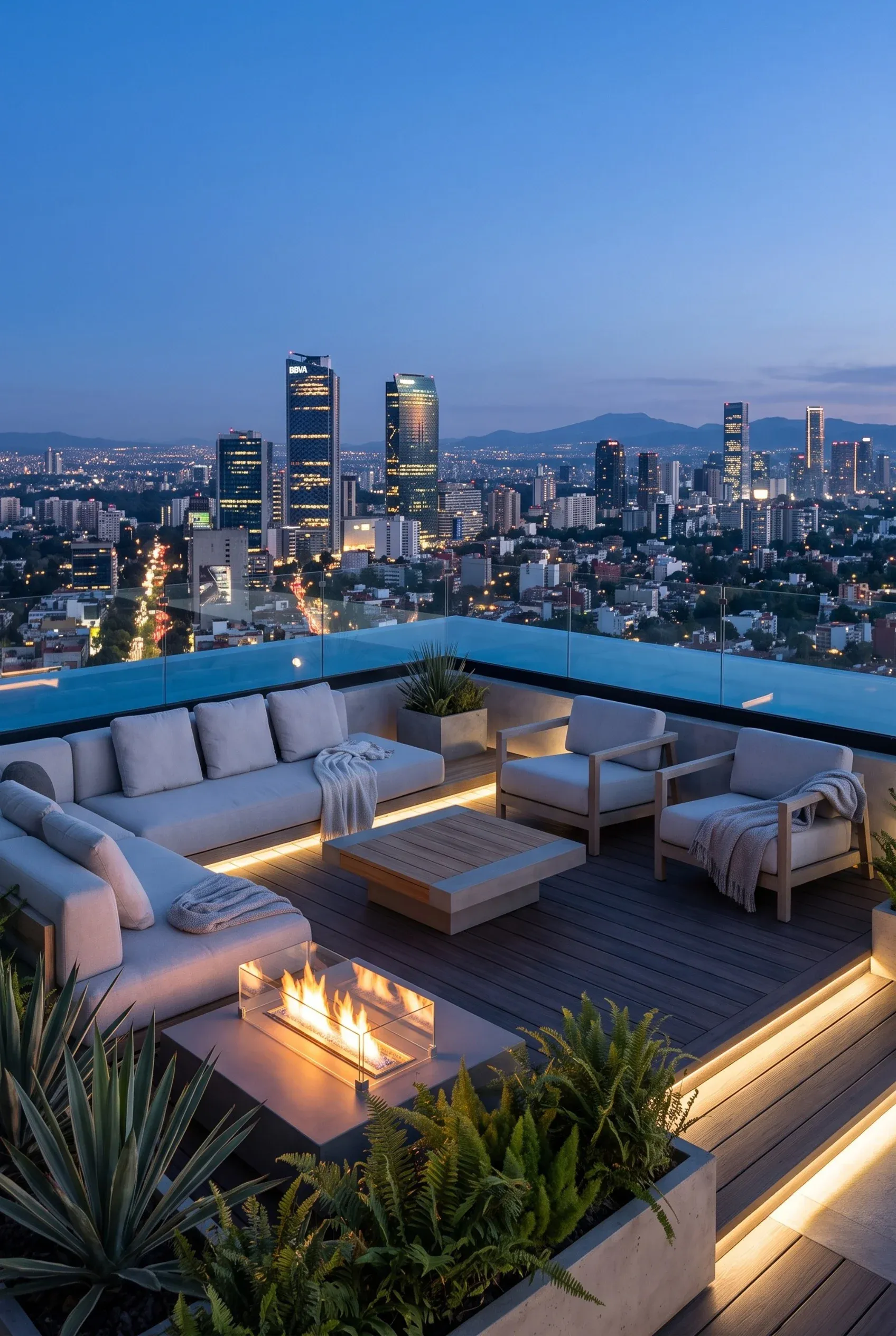 Azotea con área de lounge, fogata moderna y barandal de vidrio con vista a la ciudad iluminada, diseño de exteriores de RBA Residences en Zapopan.