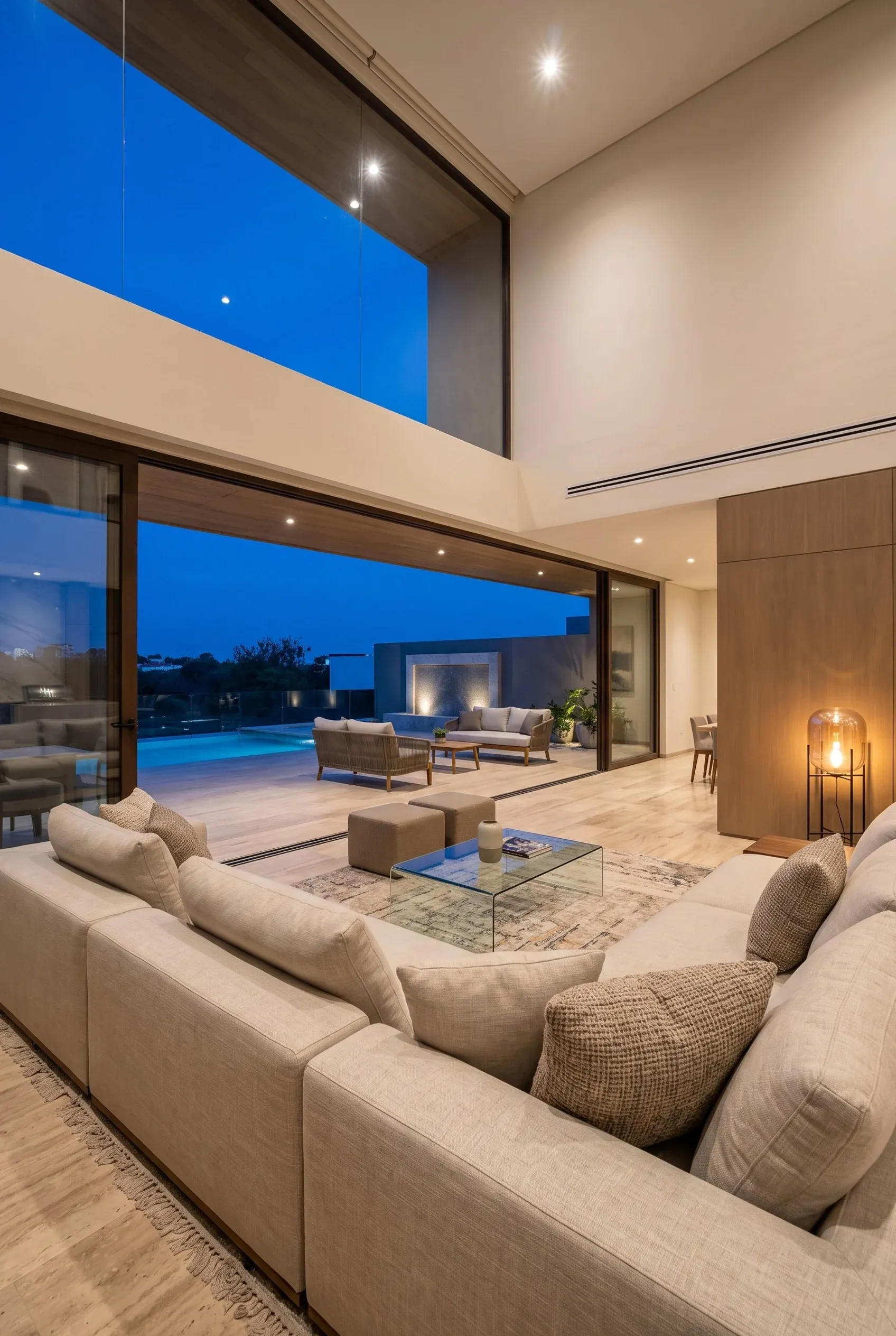 Sala de estar de una residencia de lujo por la noche con iluminación ambiental cálida, acabados premium y diseño contemporáneo de RBA Residences.