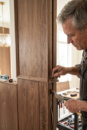 Carpintero marcando e instalando cuidadosamente molduras de madera personalizadas en una columna con paneles de pared durante la instalación de ebanistería interior, acabados artesanales de RBA Residences en Zapopan.